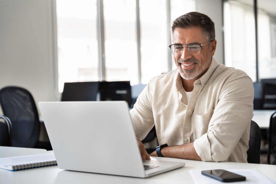 Smiling businessman working on laptop in modern office.