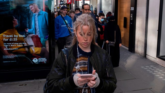 A woman checks her smartphone in London