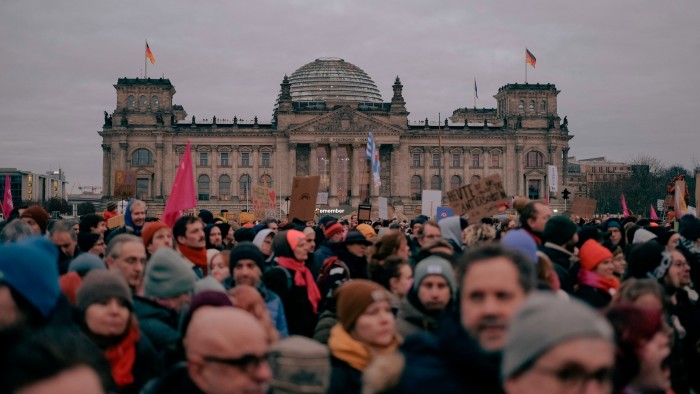 Protestors holding flags and placards in front of the Reichstag parliament building in Berlin