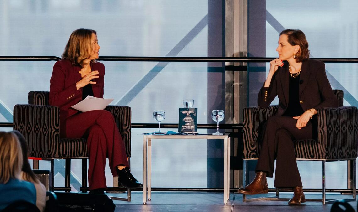 Two women sit on a stage having a conversation