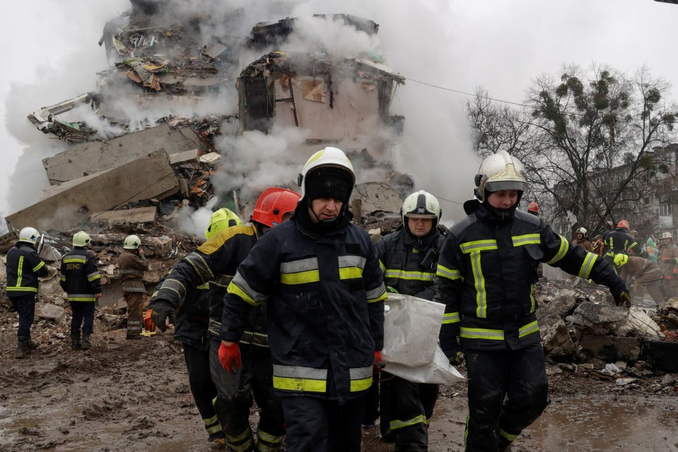 Rescuers carry a body from a bombed-out building.