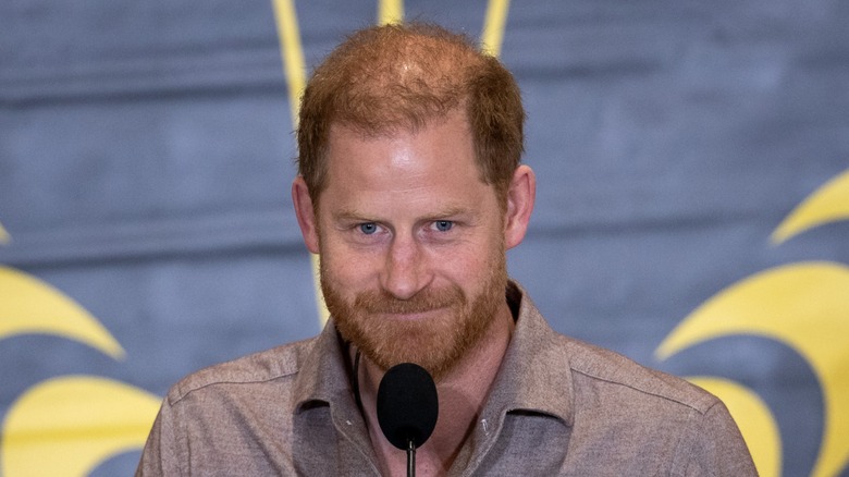 Prince Harry smiling at a microphone in November 2024.