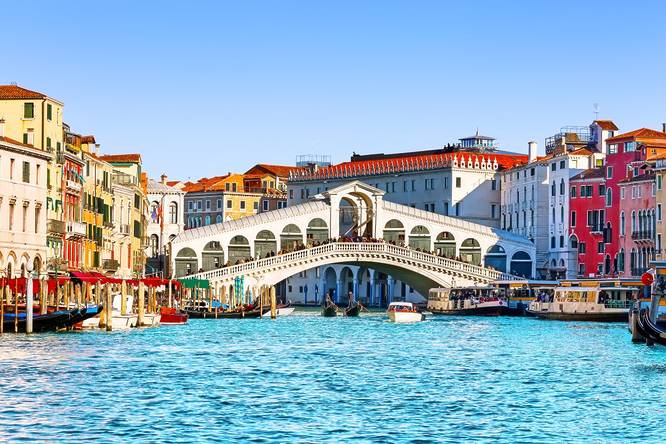View of Grand Canal with Rialto Bridge and gondoliers in Venice