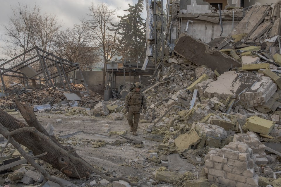 A Ukrainian soldier surveys the rubble of a missile-damaged building in Izyum.