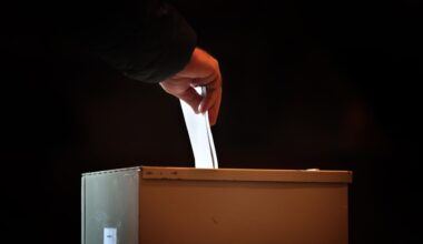 Ein Wähler steckt in einem Wahllokal seinen Stimmzettel in eine Wahlurne.