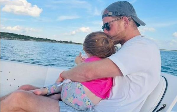 Prince Harry holding Princess Lilibet on a boat.