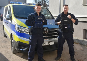 Dwóch policjantów na tle radiowozu