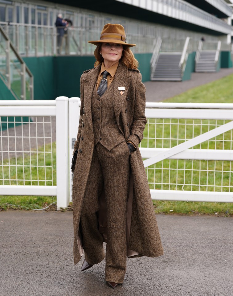 Woman in brown suit and hat at a race course.