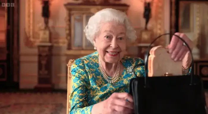 Queen Elizabeth II holding a marmalade sandwich.