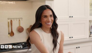 A photograph of Meghan, Duchess of Sussex, smiling while wearing a sleeveless white jumper