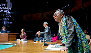Aïcha Kossoko as Tanzania, Kwong Loke as China, and Andrea Gatchalian as Kiribati standing at their seats and leaning forward in objection.