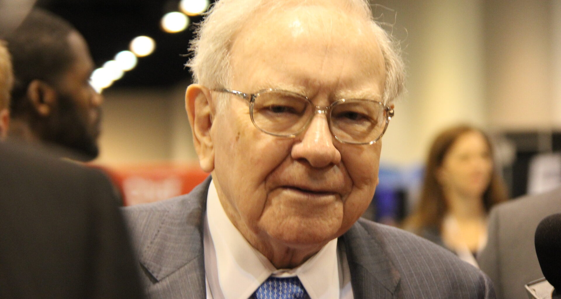 Warren Buffett surrounded by people at Berkshire Hathaway's annual shareholder meeting.