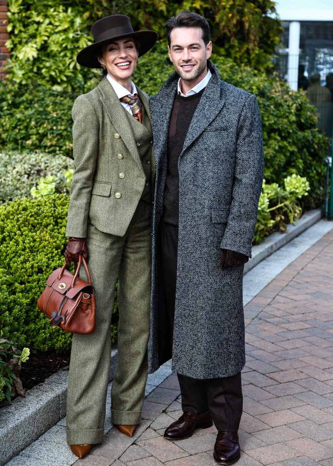 A man and woman in tweed suits standing outdoors.