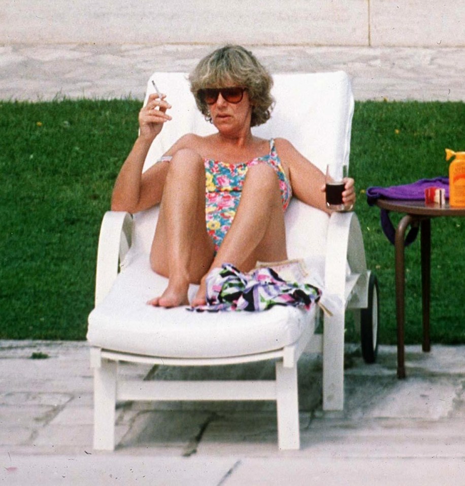 Camilla Parker Bowles sunbathing by a pool, smoking a cigarette.