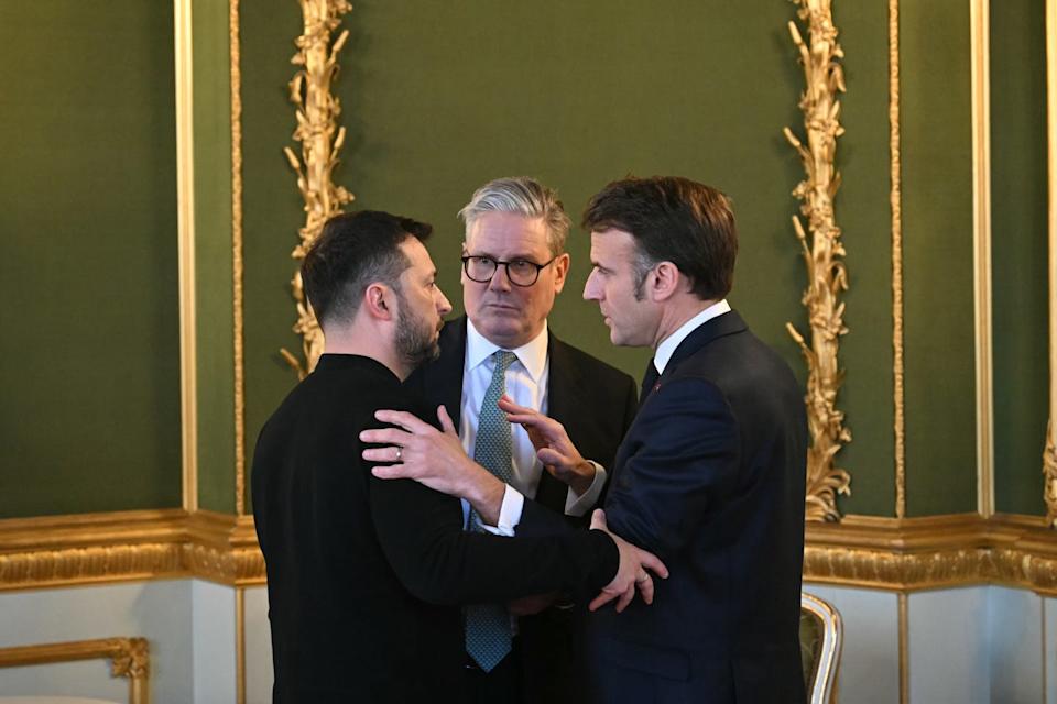 Three men embrace in a green room.