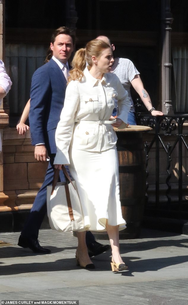 She tied her hair back into a sleek ponytail and clutched an oversized white and brown bag