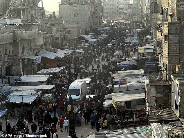 Palestinians shop in a market set up among the rubble of buildings destroyed in Israeli airstrikes in Khan Yunis