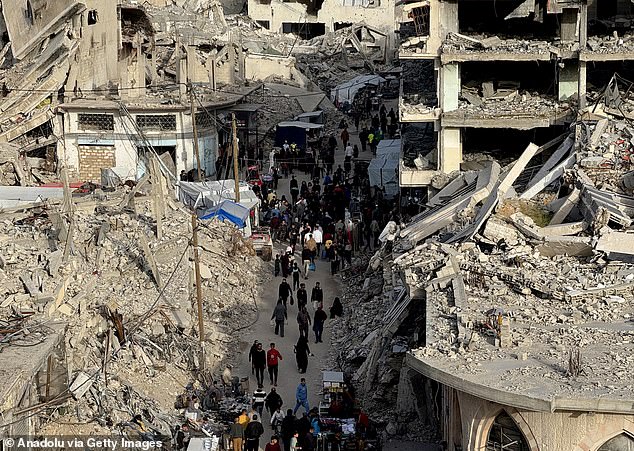 Palestinians shop ahead of Eid al-Fitr in a market set up among the rubble of buildings destroyed in Israeli airstrikes in Khan Yunis, Gaza, on March 29