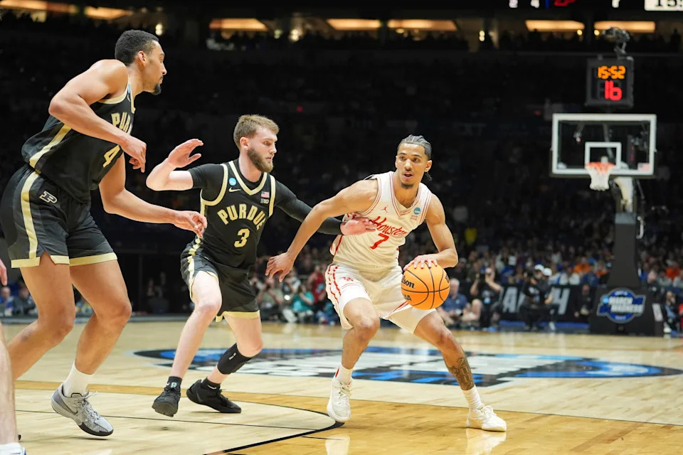 Houston's Milos Uzan (7) heads to the basket as Purdue's Braden Smith (3) and Trey Kaufman-Renn (4) defend during the first half in the Sweet 16 of the NCAA college basketball tournament Friday, March 28, 2025, in Indianapolis. (AP Photo/Michael Conroy)