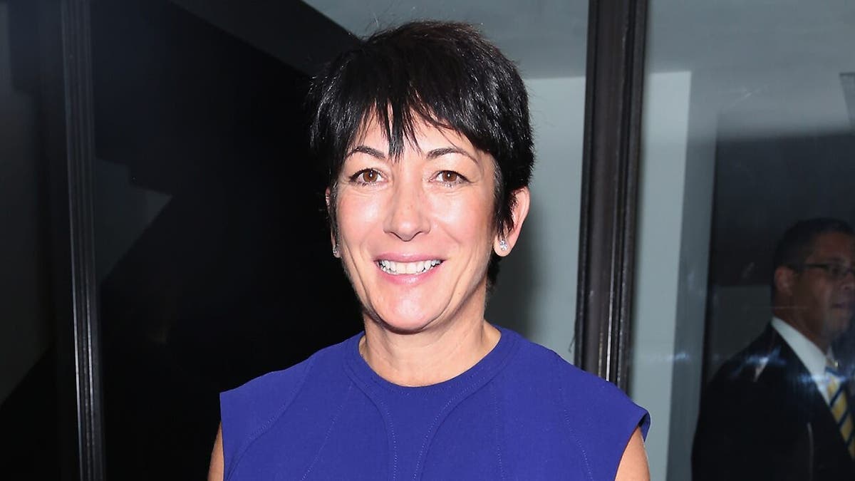 A close-up of Ghislaine Maxwell wearing a sleeveless blue dress smiling.