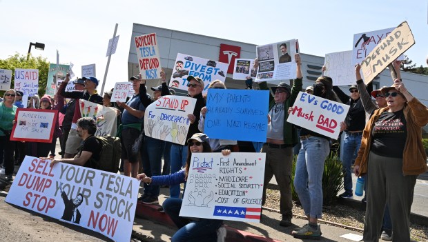 Demonstrators gather outside a Tesla dealership to protest Tesla CEO...
