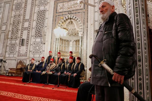A man holds a traditional sword next to a group...