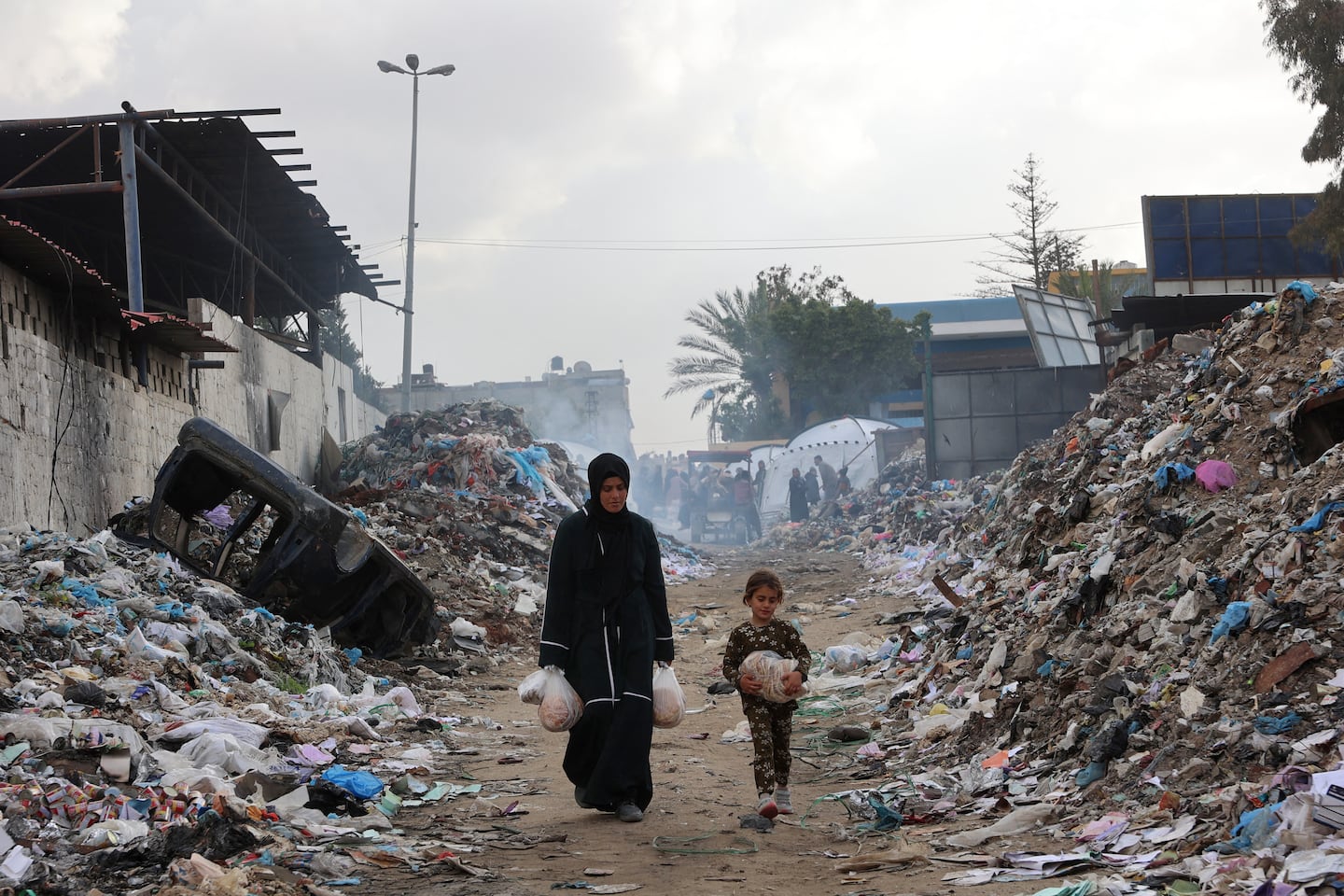 Displaced Palestinians carry food near a camp set up at a landfil in the Yarmuk area in Gaza City on March 20.