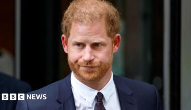 Prince Harry, Duke of Sussex, pictured in a dark suit against a black backdrop