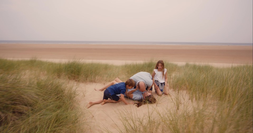 three children are playing in the sand on a beach