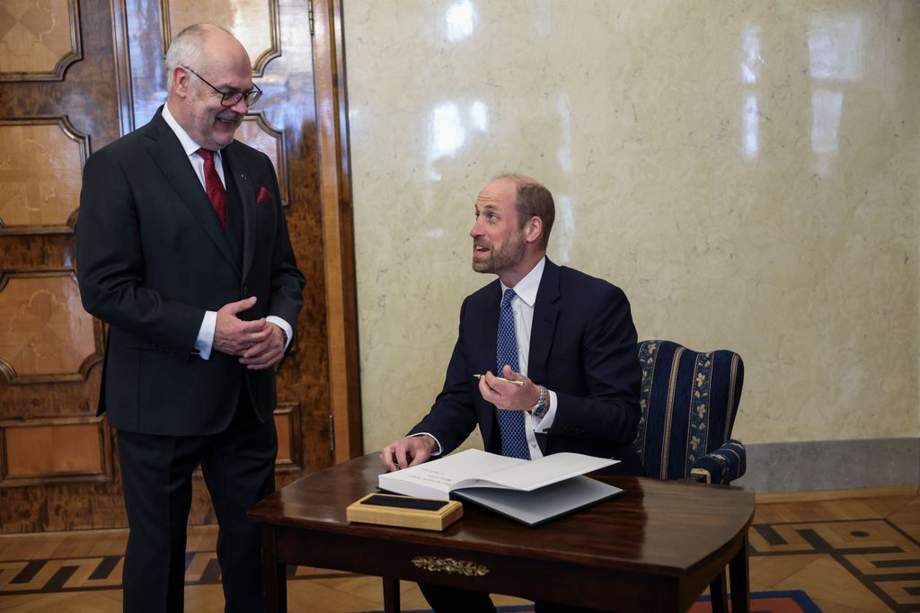 William signing a guest book next to Estonian President Alar Karis