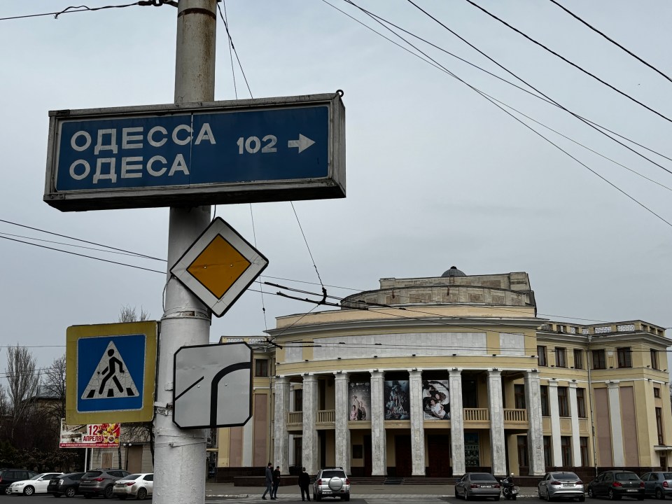 Road sign indicating direction to Odessa (102) and a building in the background.