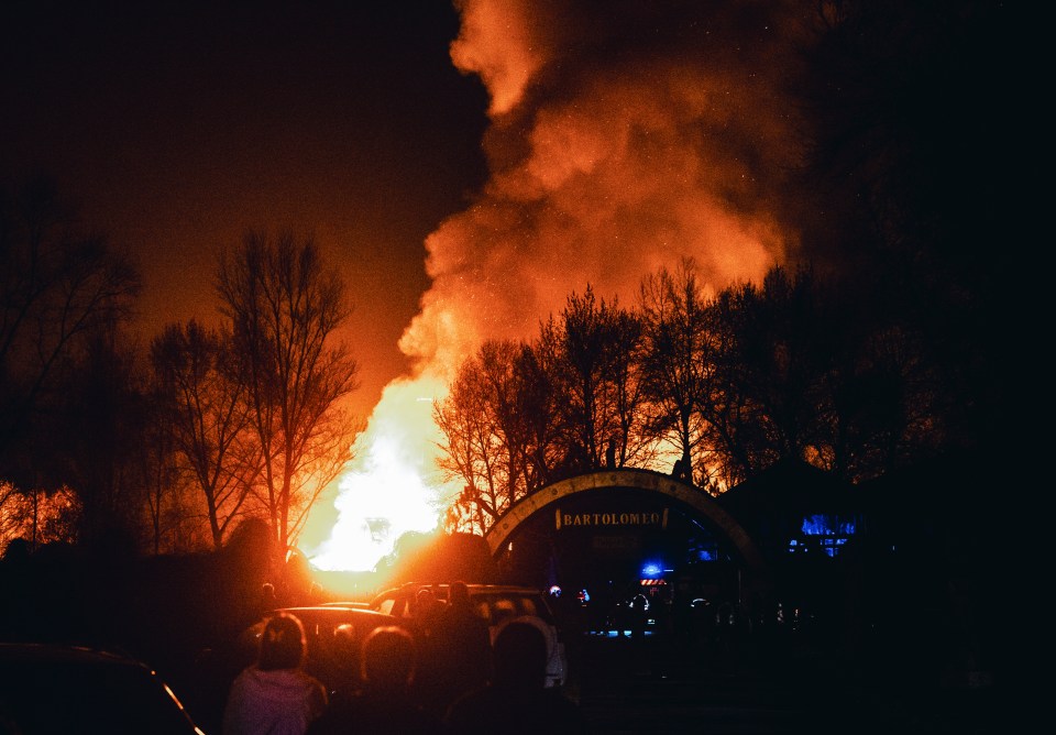 People watch the burning Hotel Bartolomeo after a drone strike in Dnipro, Ukraine.