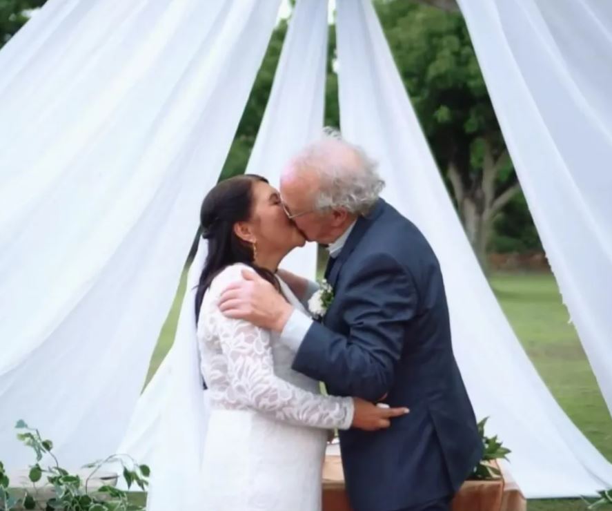 A bride and groom kissing at their wedding ceremony.