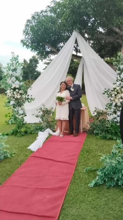 A bride and groom stand under a white canopy at their wedding ceremony.