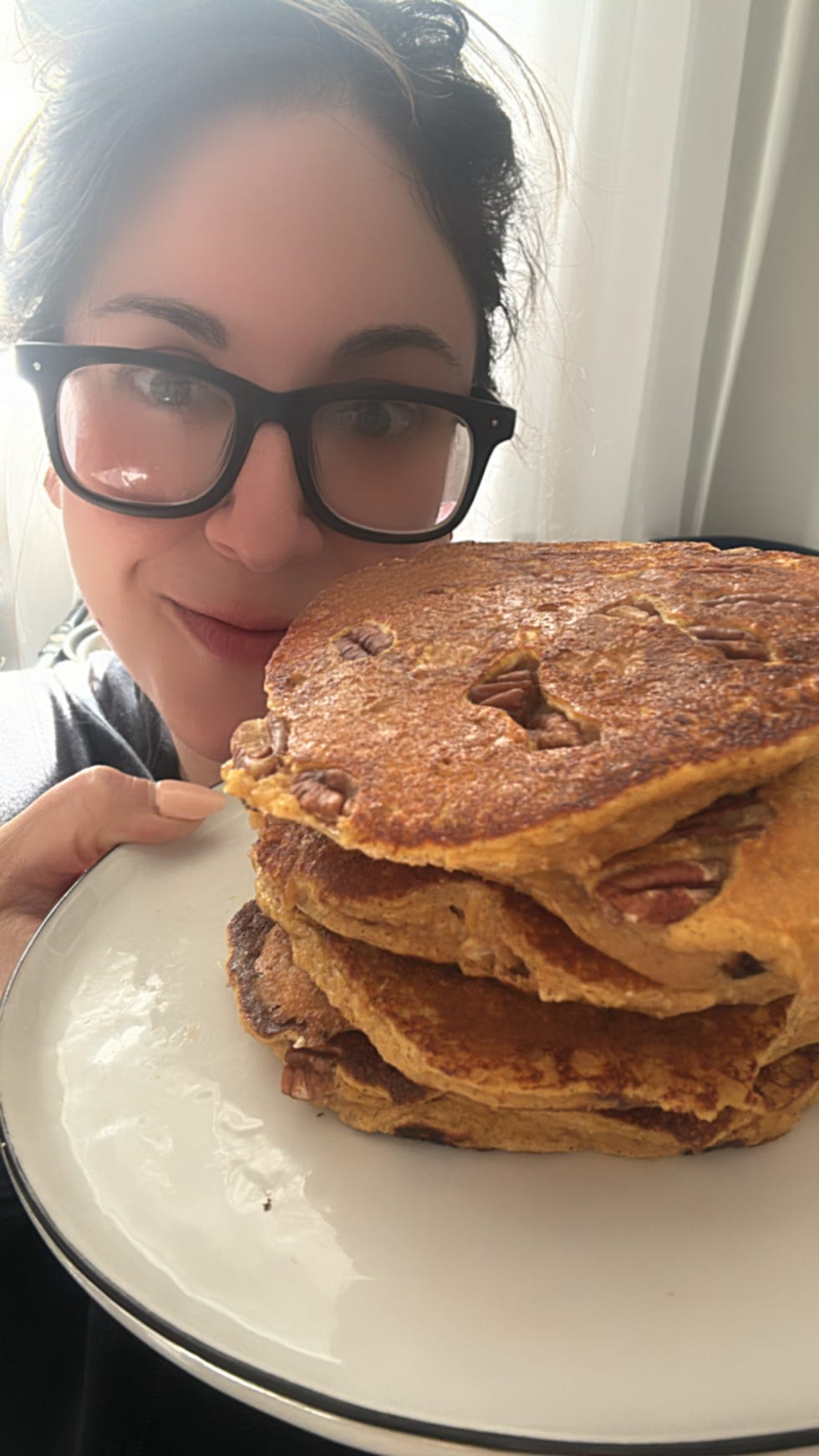writer jessica wrubel holding a plate of pumpkin protein pancakes, one of many recipes in the wh high protein meal prep manual