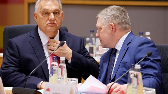 Two men in suits sit at a conference table