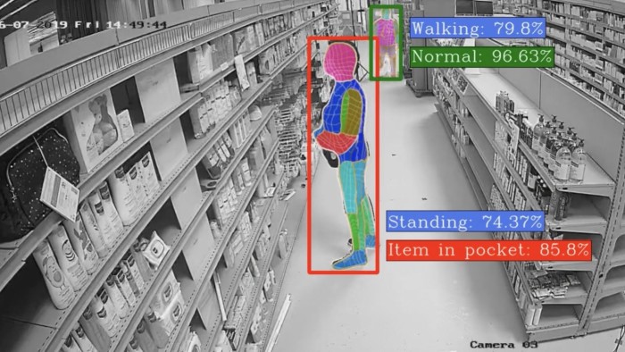 Black-and-white CCTV footage in a shop aisle with AI detection overlay identifying a person possibly placing an item in their pocket with 85.8% certainty
