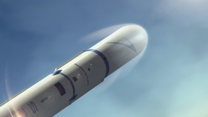 A close-up view of a white and blue rocket labeled “Spectrum” ascending into the sky