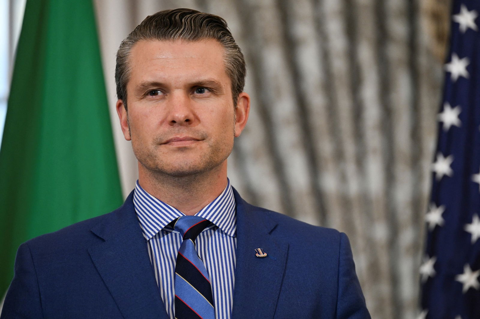 US Defense Secretary Pete Hegseth poses for a photo wearing a navy suit