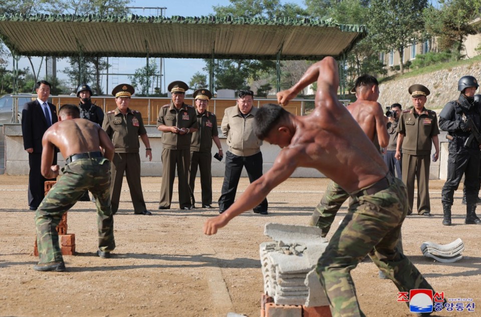 North Korean soldiers breaking bricks with their bare hands, observed by Kim Jong-un.