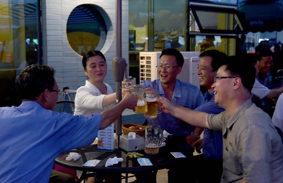 Photo of a group of North Koreans toasting with beer at an outdoor beer festival.