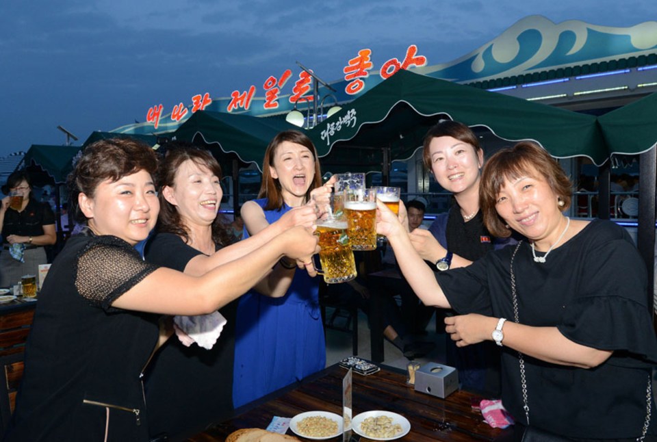 Women toasting beer mugs at a North Korean beer festival.