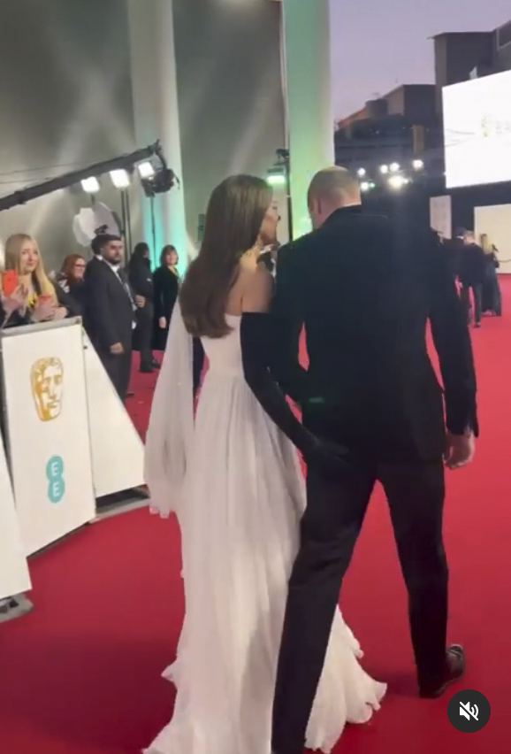 a woman in a white dress and black gloves is walking on a red carpet