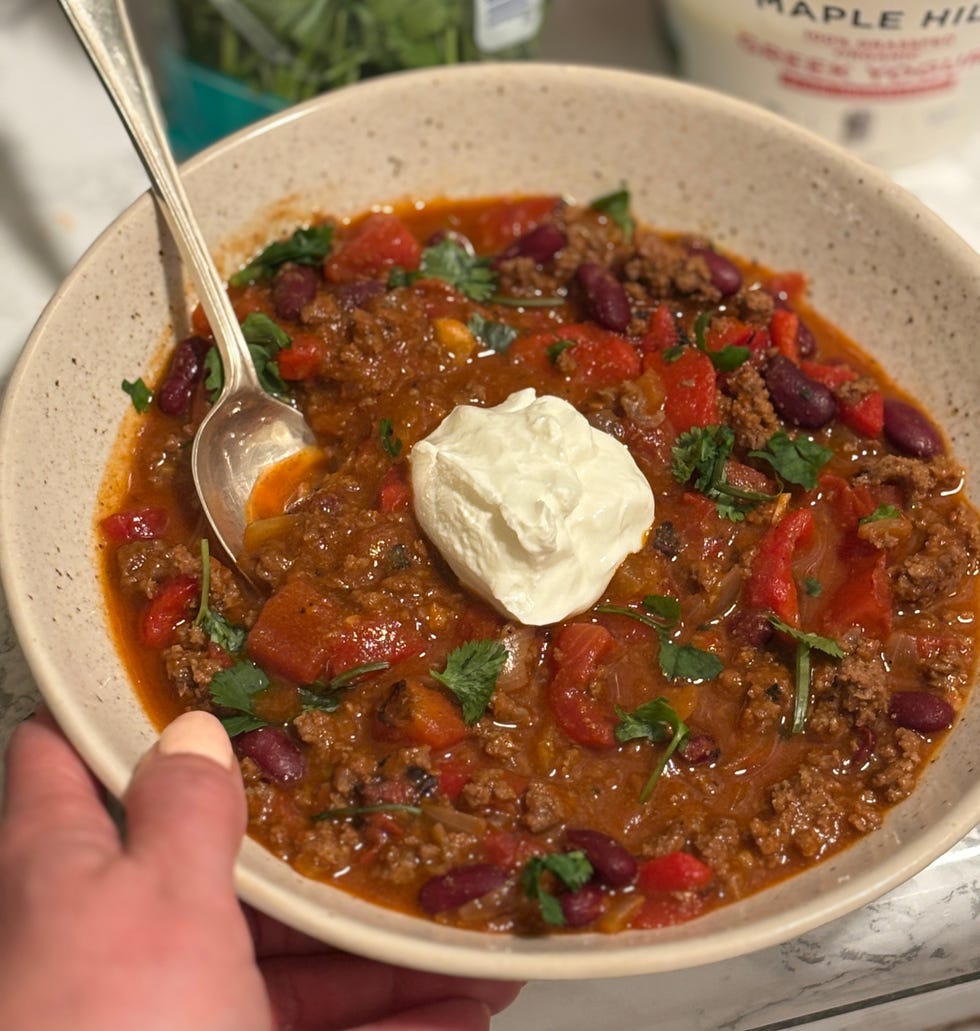 writer jessica wrubel holding a bowl of three bean bison chili, a recipe in the wh high protein meal prep manual