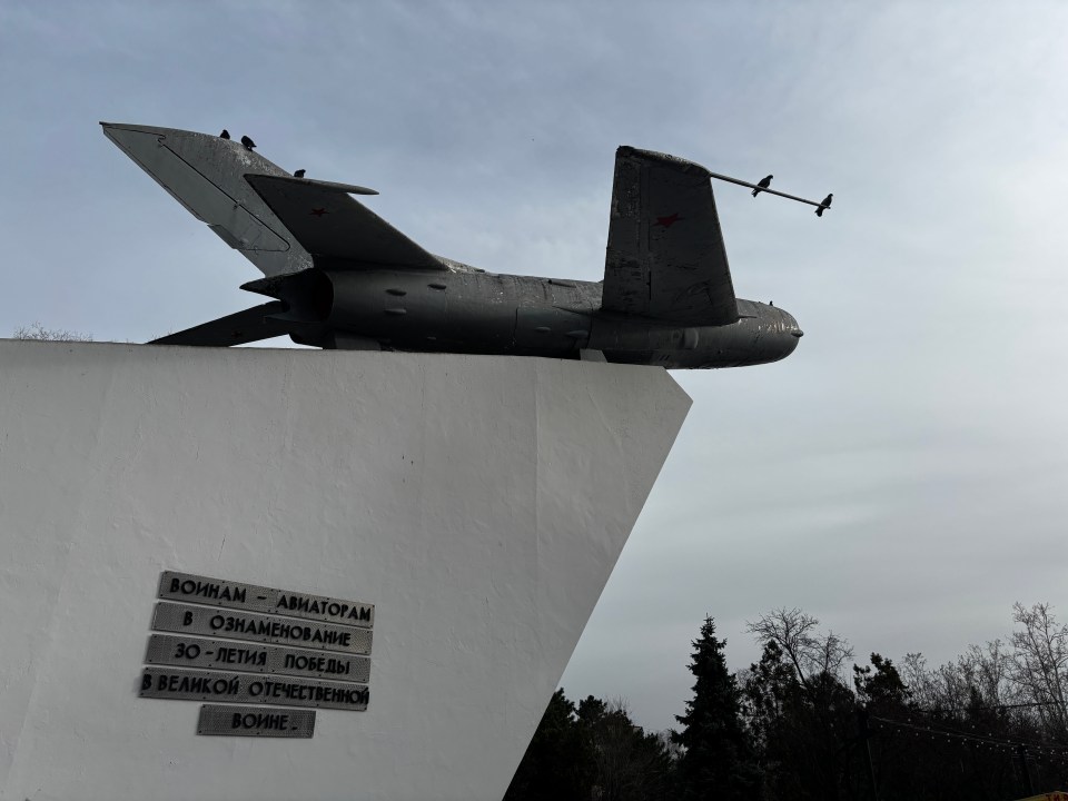 A weathered military jet mounted on a white monument.