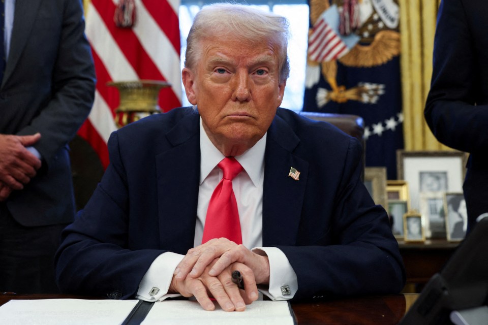 Donald Trump standing in front of American flags.