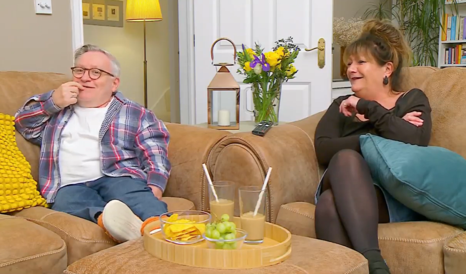 A man and woman sitting on a couch together.