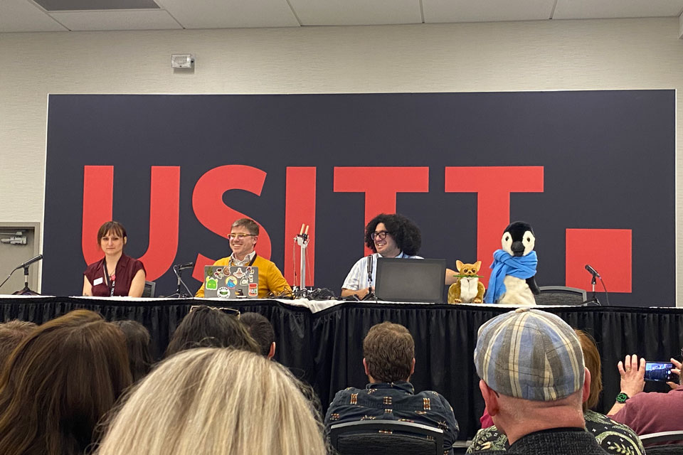 People sitting at a table infront of a large crowd.
