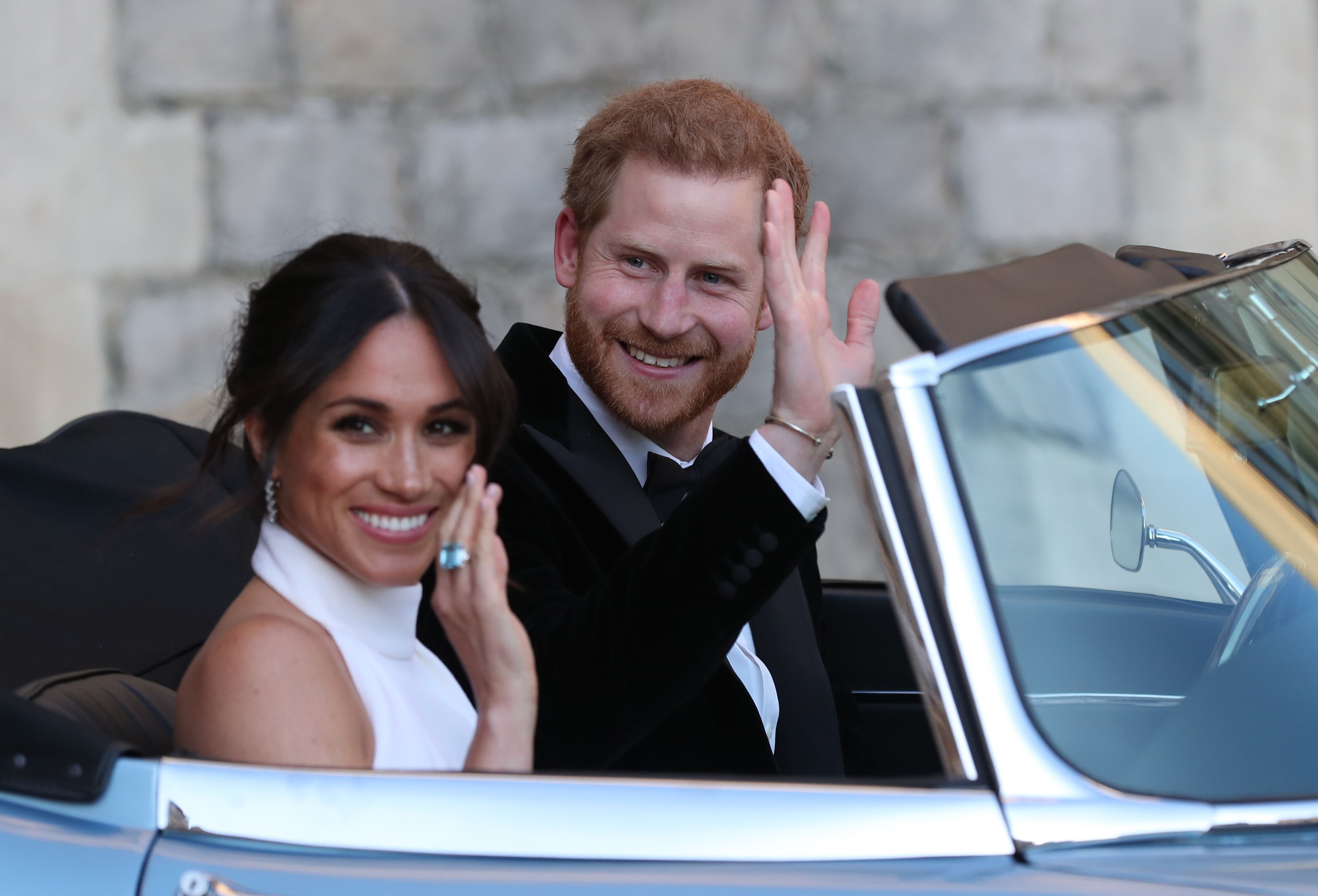 Prince Harry and Meghan Markle waving from a car after their wedding.