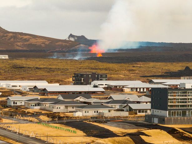 The volcanic eruption is seen in the background near the town of Grindavik, on the Reykjanes Peninsula, Iceland, Tuesday, April 1, 2025.